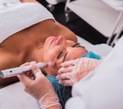 Cosmetologist making mesotherapy injection treatment with dermapen on face of adult woman for rejuvenation in the spa center.