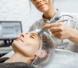 Cosmetologist making vacuum hydro peeling on the forehead region to a woman at the luxury beauty salon. Concept of a professional facial treatment